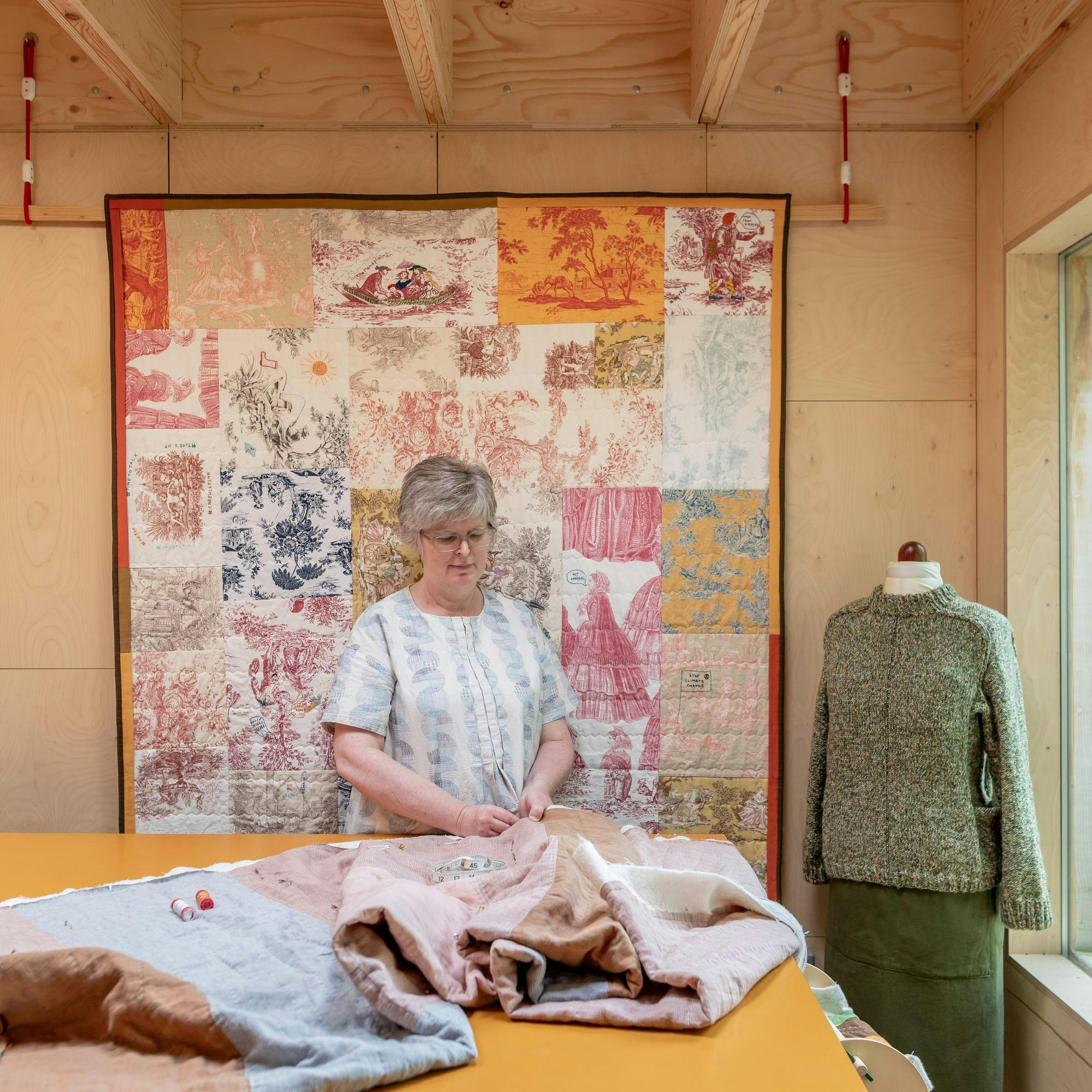 Image of woman making tapestry cloth inside garden shed