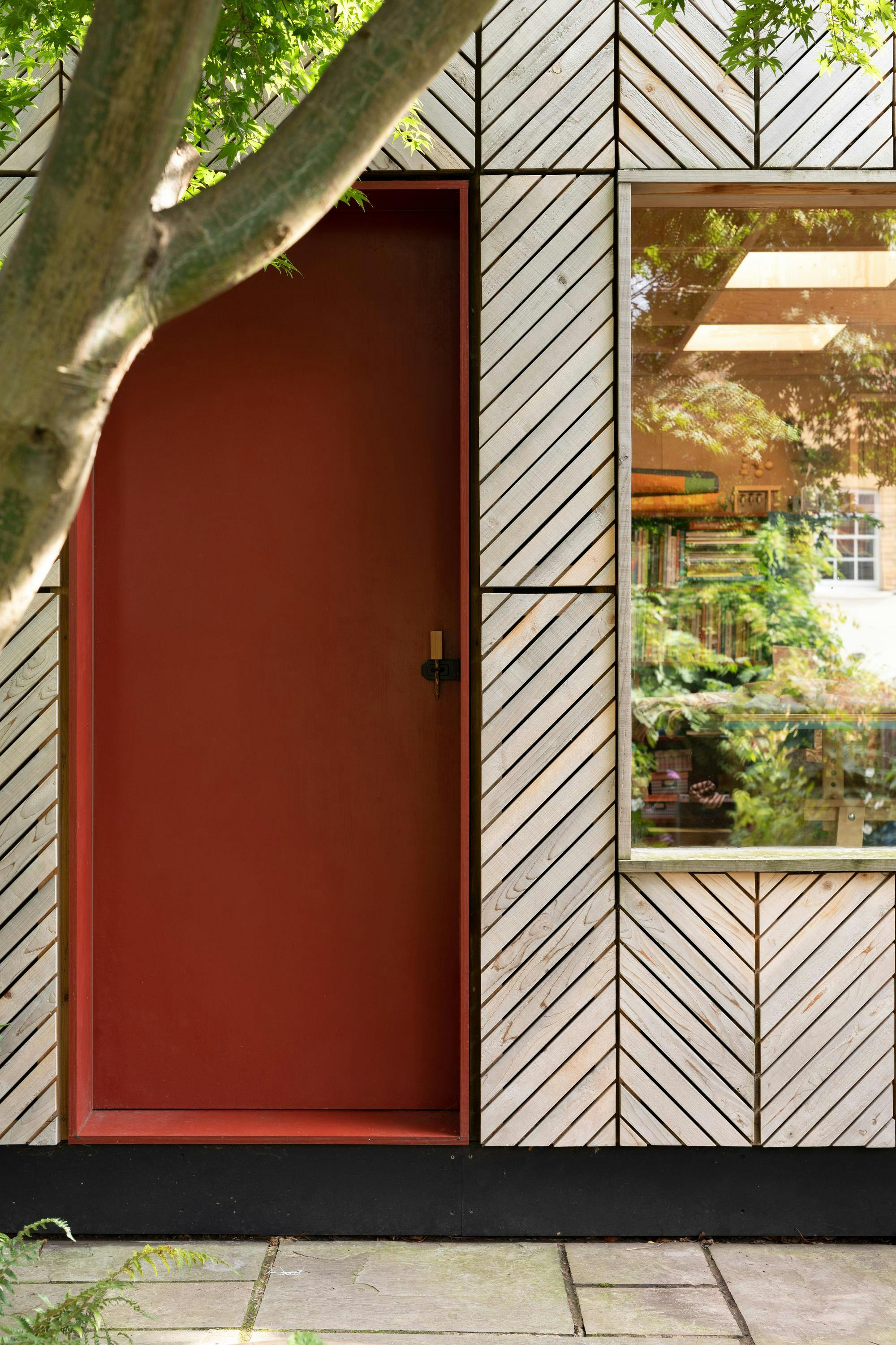 Image of garden shed made from timber with a red front door