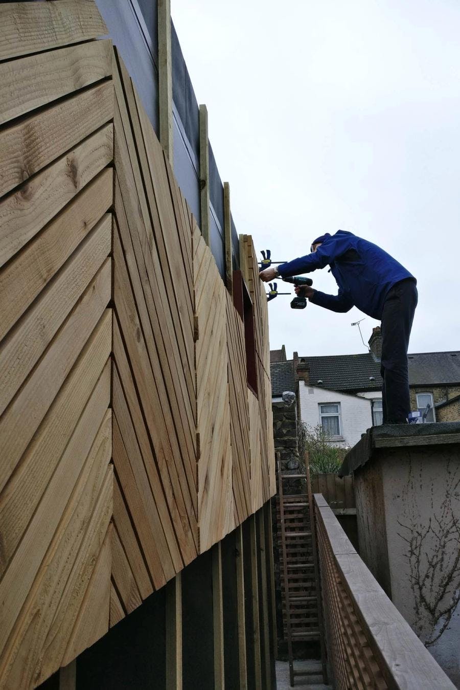 Client on roof attaching cladding panels to pod wall