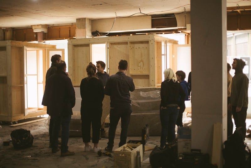 Group of students and studio members around the timber work pod